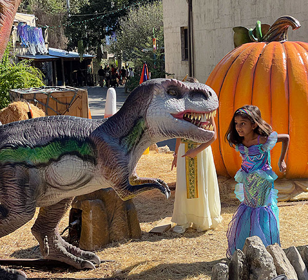 Photo - Young girl approaching an animatronic dinosaur at the San Antonio Zoo