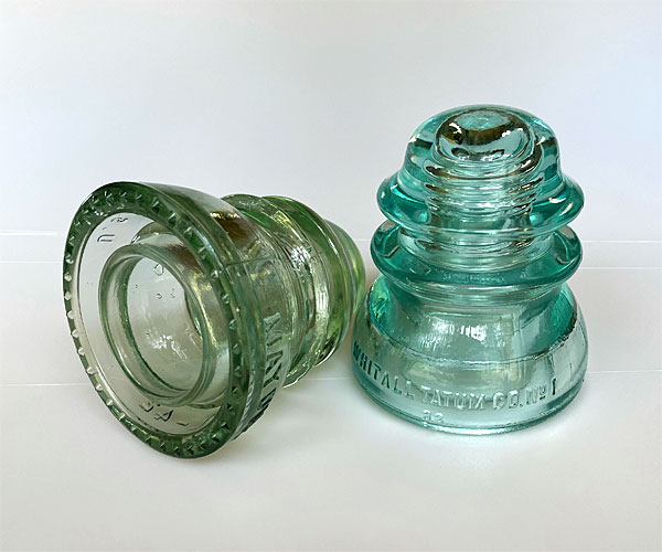 Photo - Two glass insulators, one pale green and one smoky clear color