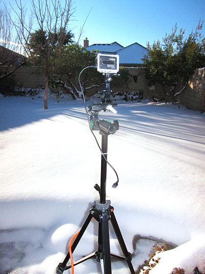 GoPro camera mounted on tripod in front of snow-covered yard