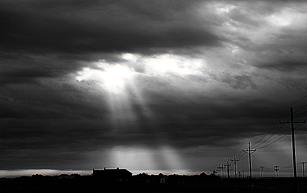 Photo - Black & white image of sun rays shining through clouds