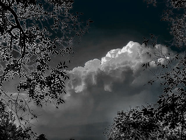 Grayscale photo: Dark storm clouds, the tops of which are glowing in the sunset