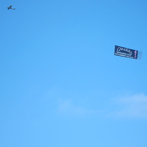 Photo: Airplane pulling a 'Gentlemans Club' banner over the ocean